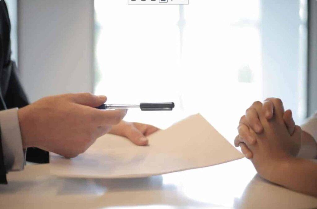 one person handing over a contract to another to be signed, representing the importance of an acceptable use policy in business