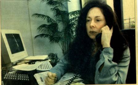 Antoinette Allocca using a landline phone on her desk while working on physical documents and holding a pen