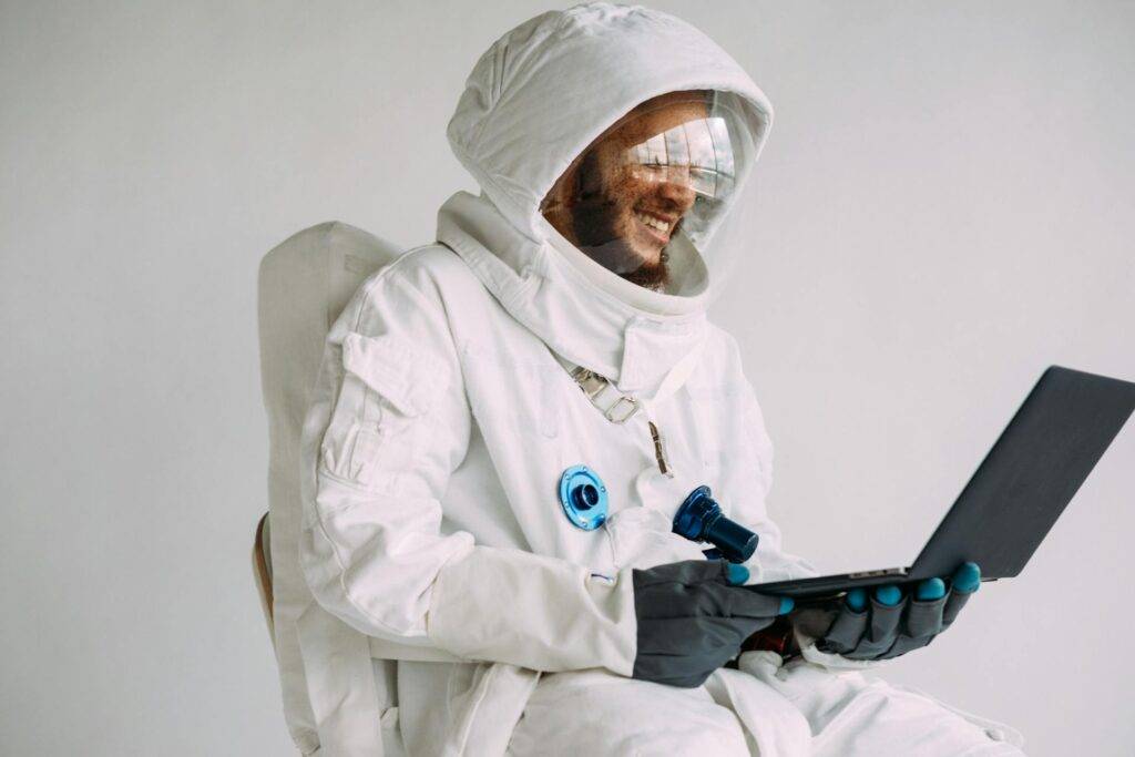 a Person in a Spacesuit Smiling while Looking at a Laptop, Representing the Importance of a Aerospace Technical Writer