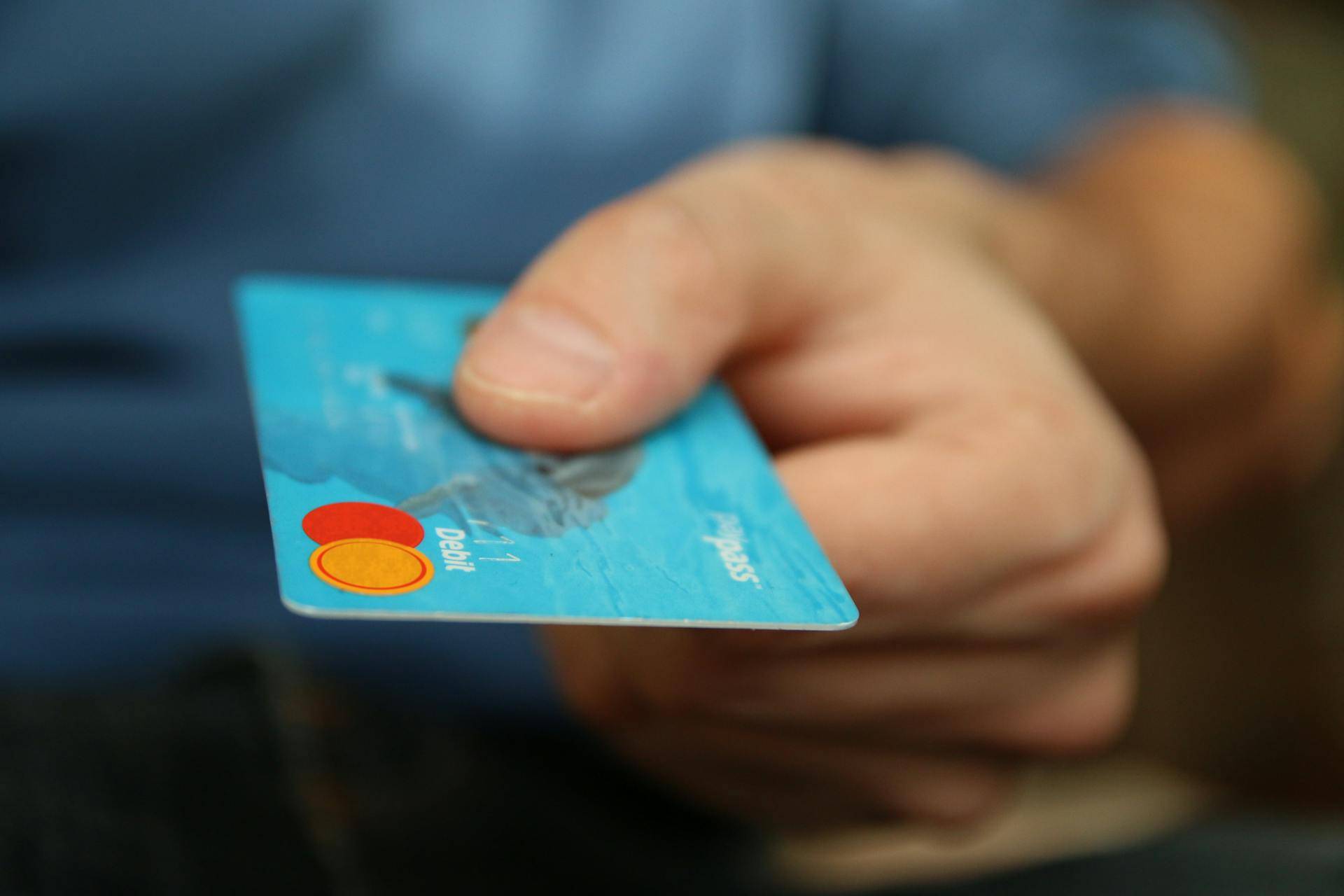 a Person handing over a Card at a Credit Union, representing the Importance of Standard Operating Procedures (SOPs) for a Workplace