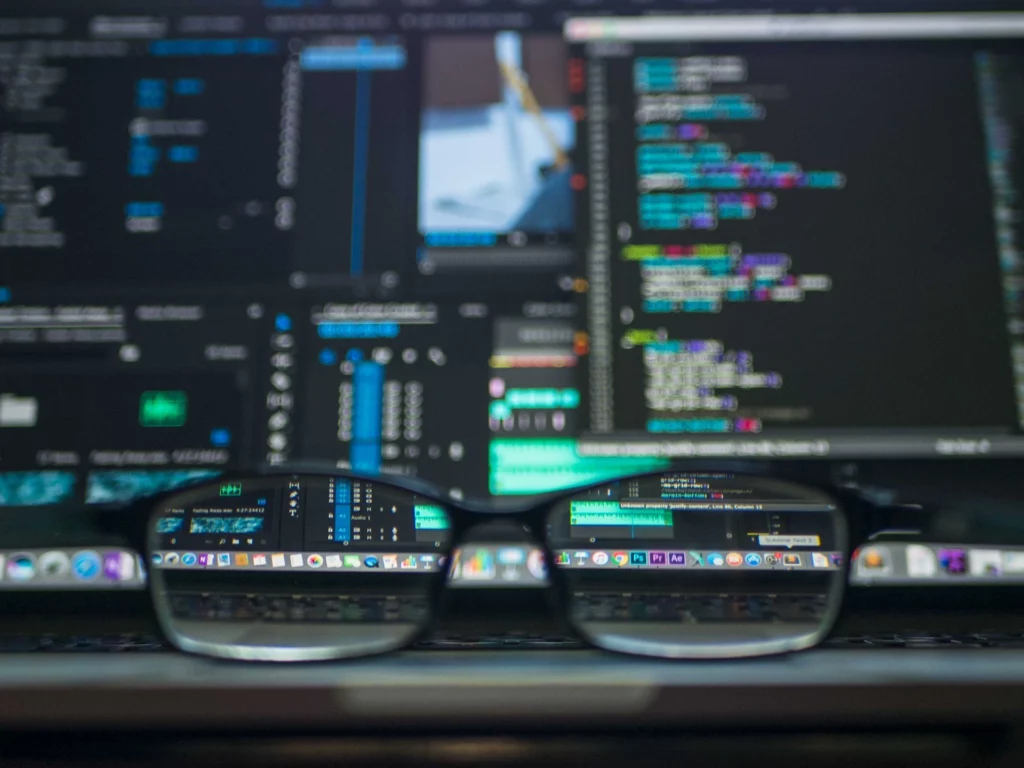 A pair of glasses in front of computer screen with code, representing the importance of good software documentation principles.