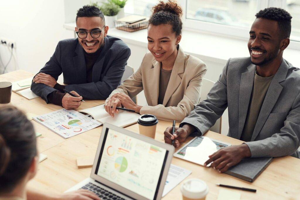 a Group of Employees Sitting at a Conference Table, Smiling, Representing the Importance of a Functional Specification Document in Reaching Success