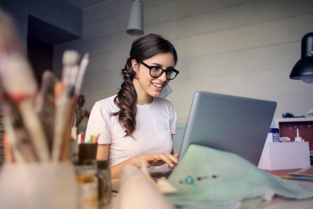 a woman wearing glasses smiling into a computer