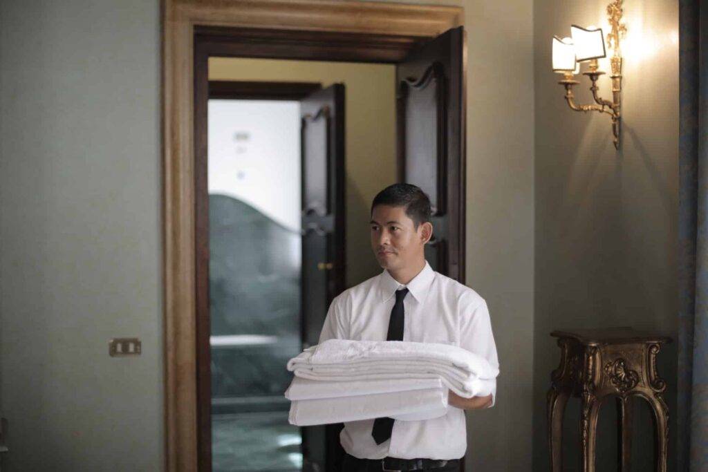 a hotel employee carrying carefully folded towels, representing the importance of a hotel staff training manual