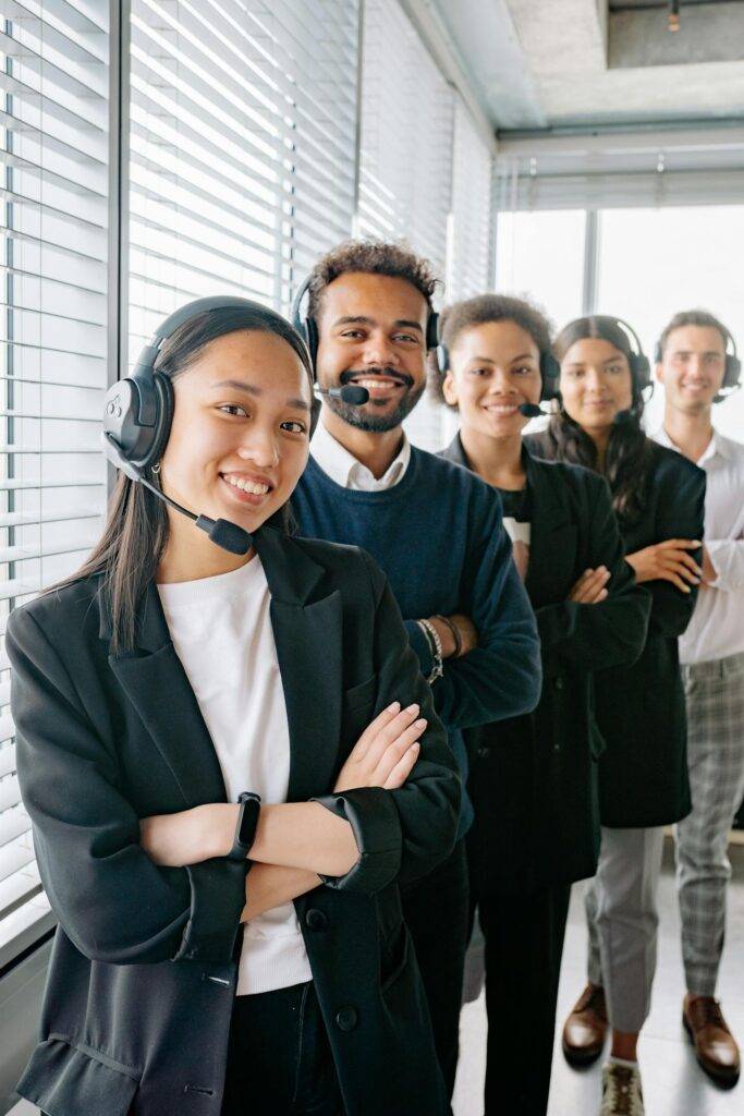 a Group of Headset Wearing Employees Smiling at the Camera, Representing the Importance of a Business Operations Manual