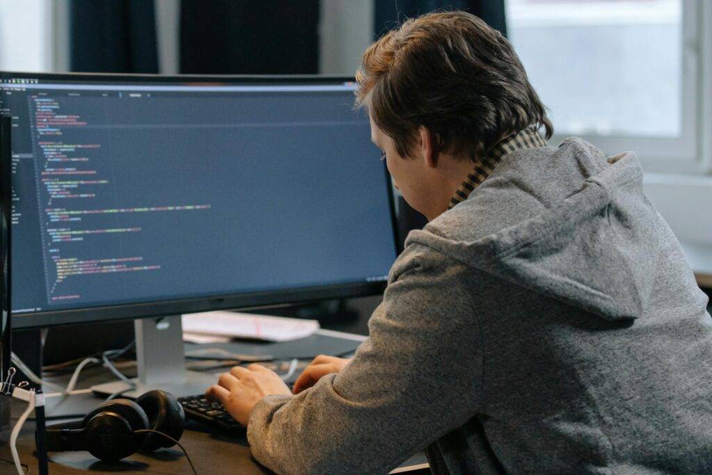 A person Working at a Computer Reviewing Code, Representing the Importance of IT Policies and Procedures Writing Services