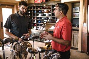 a employee helping a customer in a golf shop, representing the importance of a customer service training manual