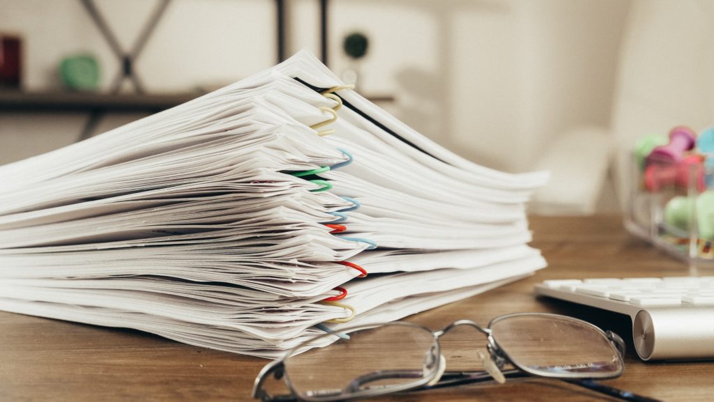 Stacks of white paper documentation on top of a desk