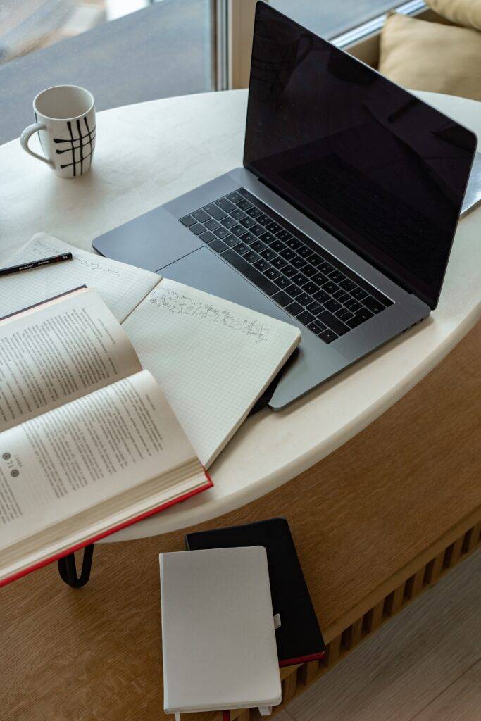 A computer and books on a table, representing the importance of documentation