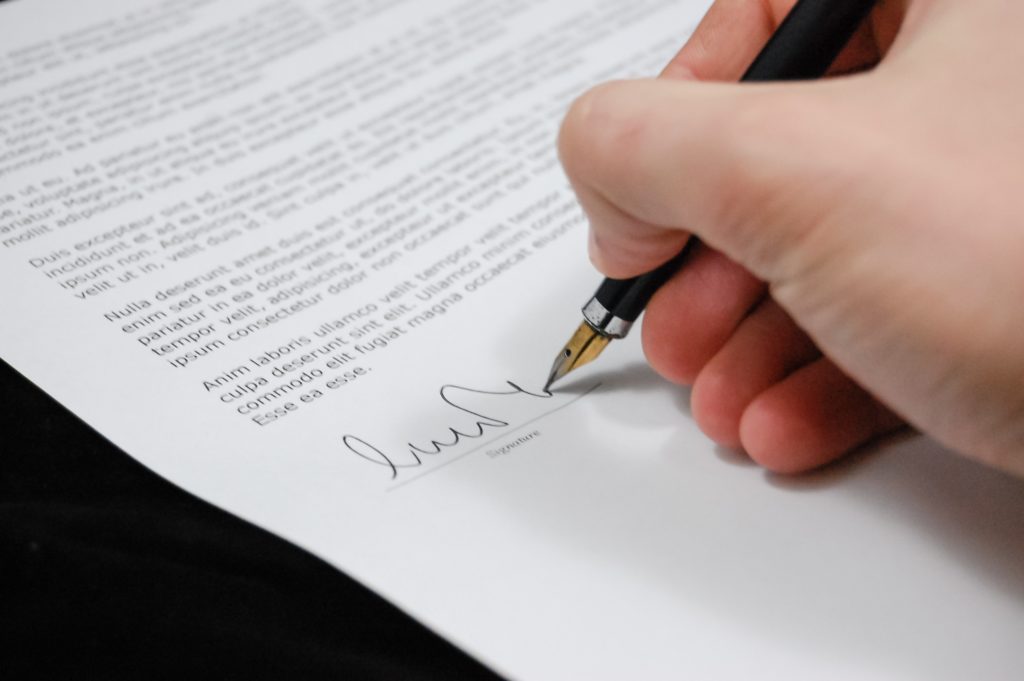 a person signing a document with a dip pen