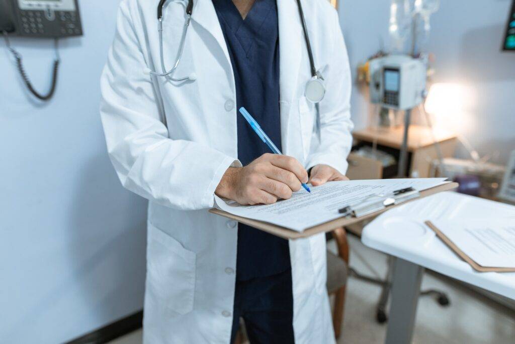 A Doctor Writing on a Clipboard, Representing the Importance of Medical Writing and Regulatory Writing in the Healthcare and Pharmaceutical Industries