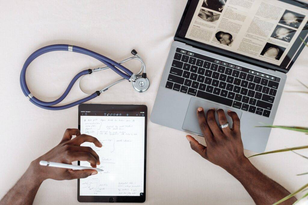 A stethoscope, laptop, and journal on a table, representing the importance of regulatory writing services