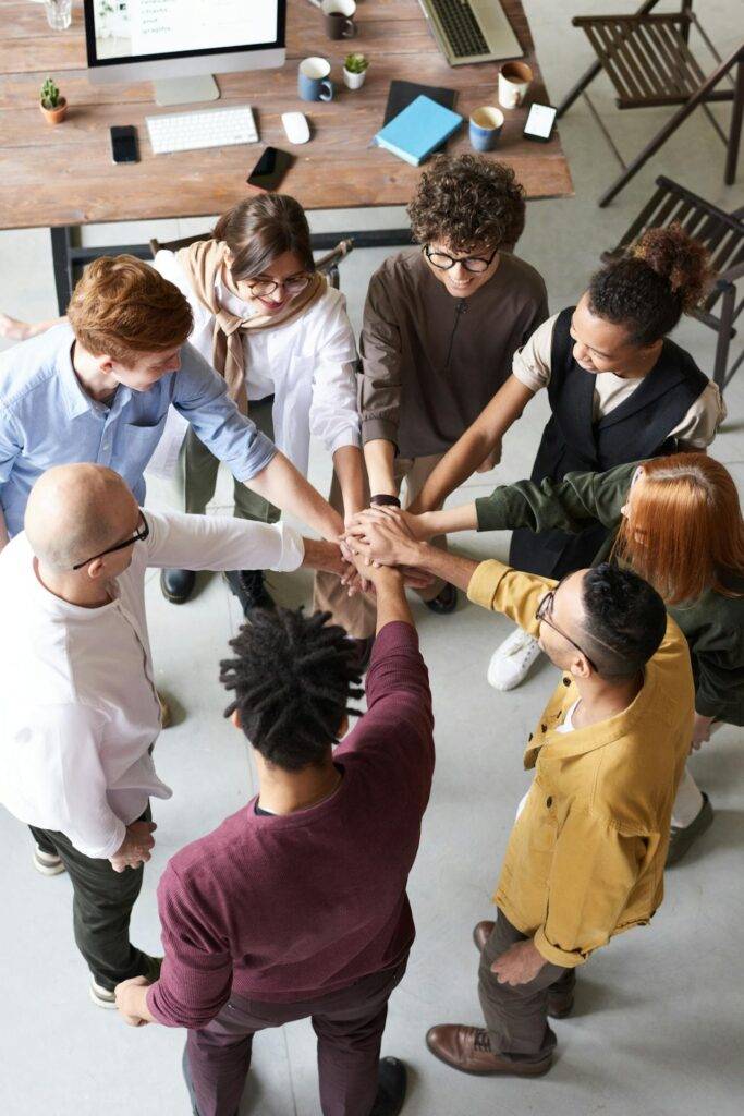 a Group of Coworkers Engaging in a Display of Teamwork with Hands Joined in the Middle of a Circle, Representing the Benefits that a Policy Manual Can Bring an Organization and the Importance of Knowing What is Included in a Policy and Procedure Manual