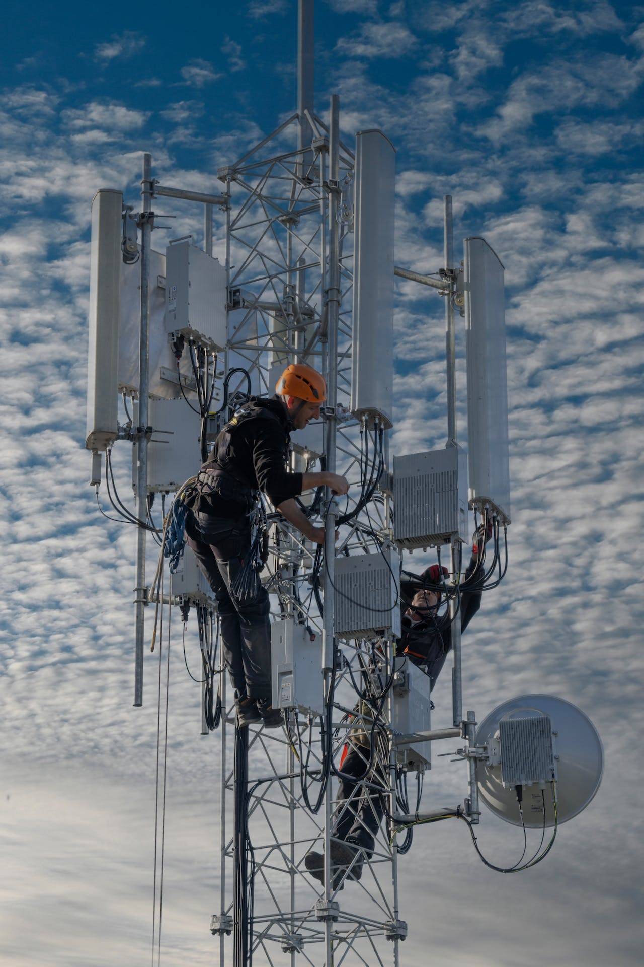 Two People Working on a Cell Tower, Representing the Importance of Technical Manuals in Providing Subsidized Cell Service