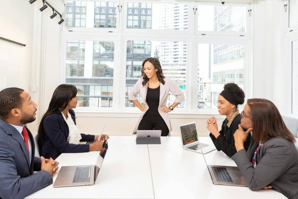 a Woman Presenting to a Team of Coworkers, Representing the Importance of Knowing What is Included in a Policy and Procedure Manual for Business Efficiency